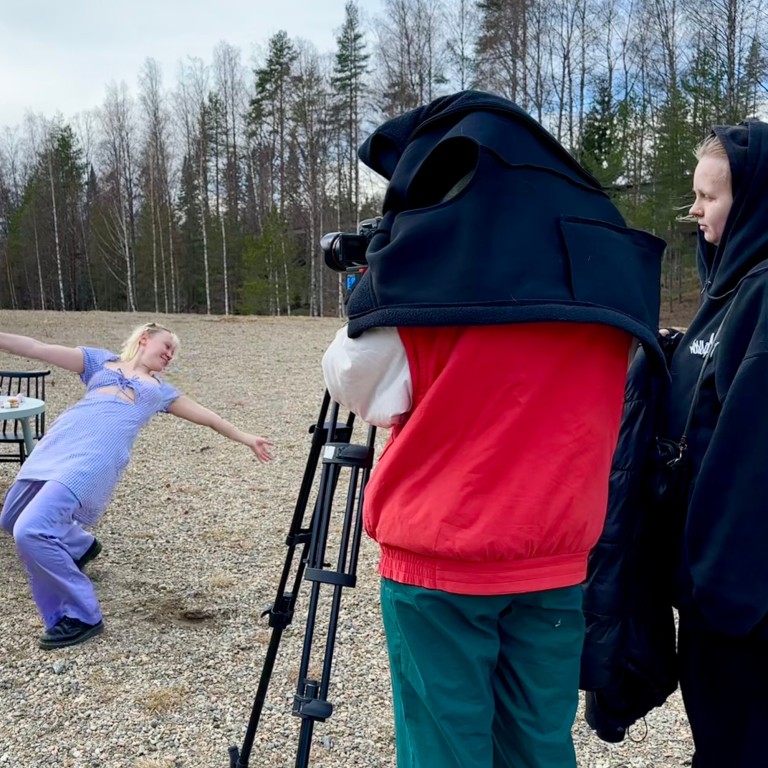 kaksi henkilöä kuvaa videokameralla kun kolmas tanssii