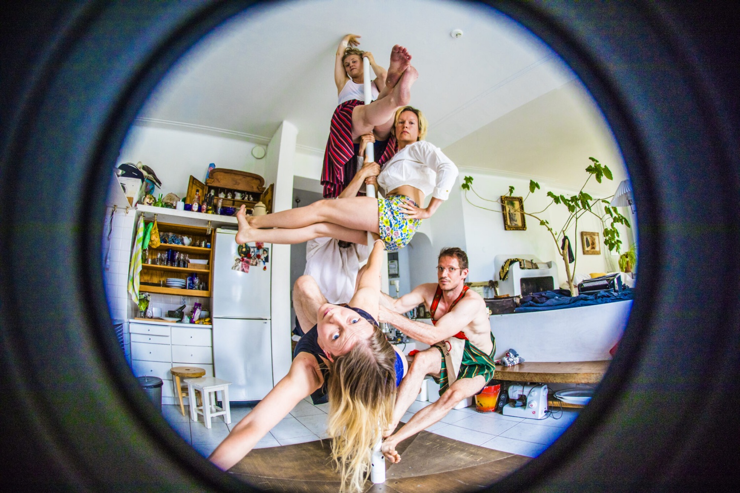 Neljä tanssijaa roikkuu olohuoneen tanssitangossa