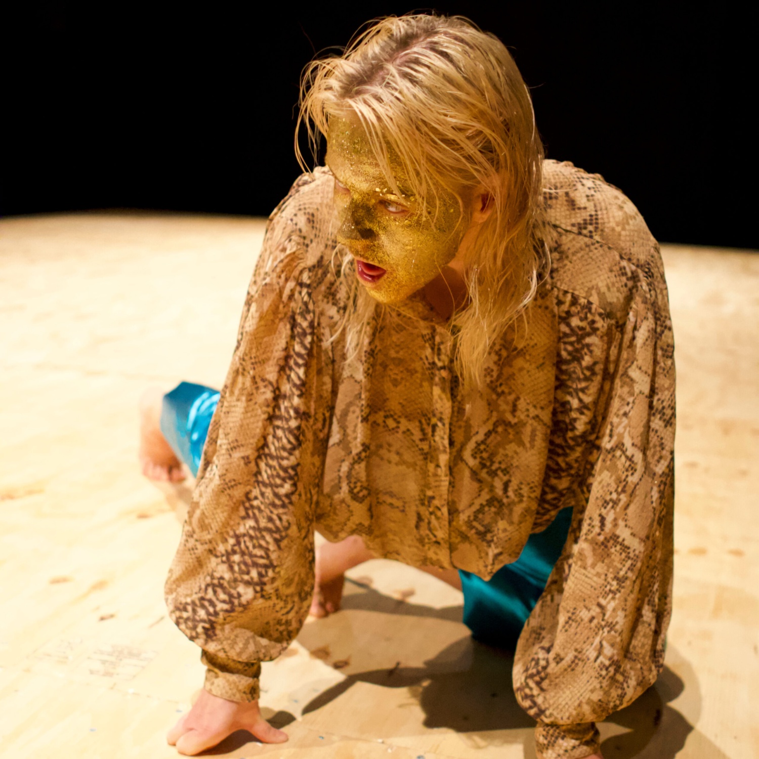 A dancer on the floor in a golden face make up