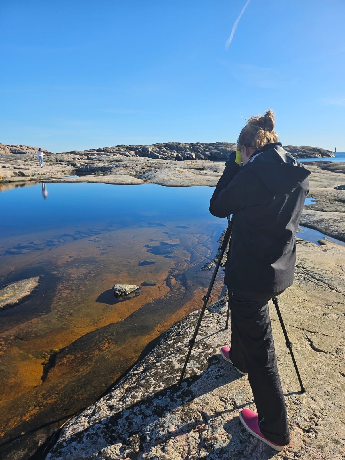 Nainen kalliolla kameran kanssa