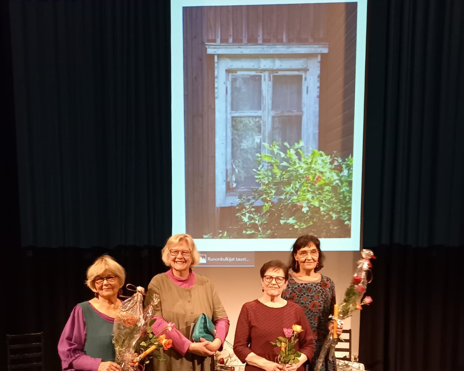 Fyra kvinnor står med blommor i famnen