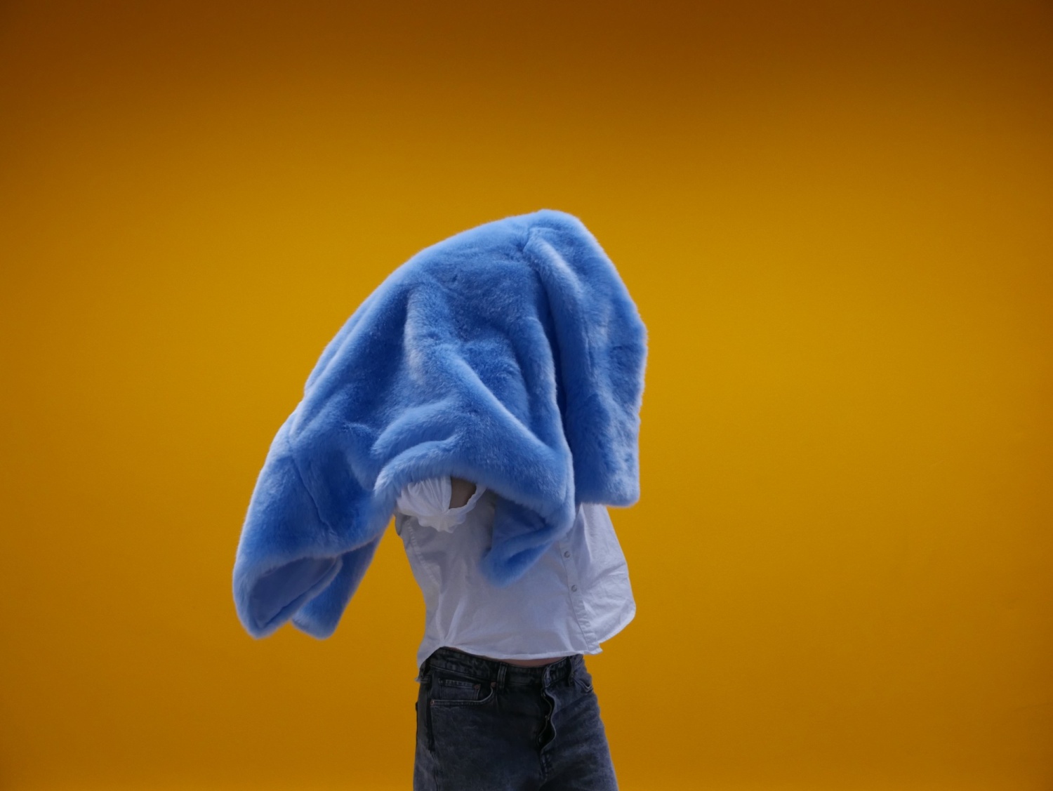 A woman holds a blue fur coat on her head