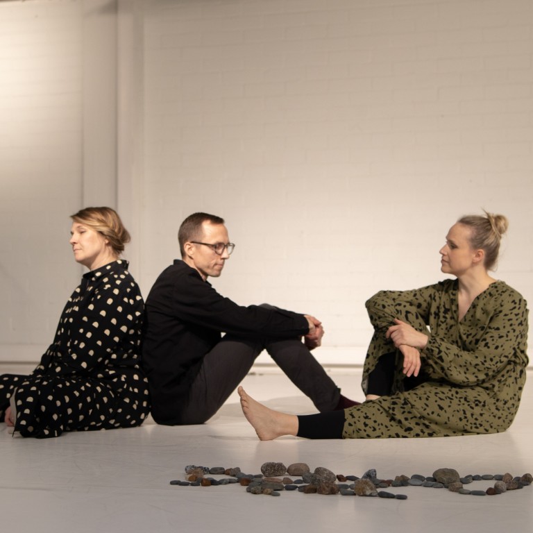 Three people sitting on a white floor