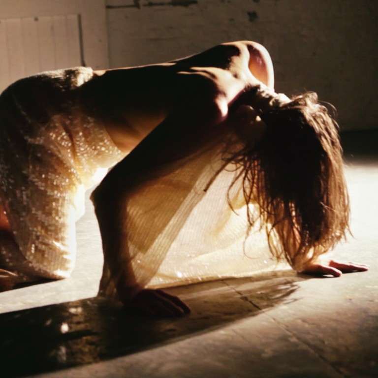 A dancer in table top positions in front of a stage light
