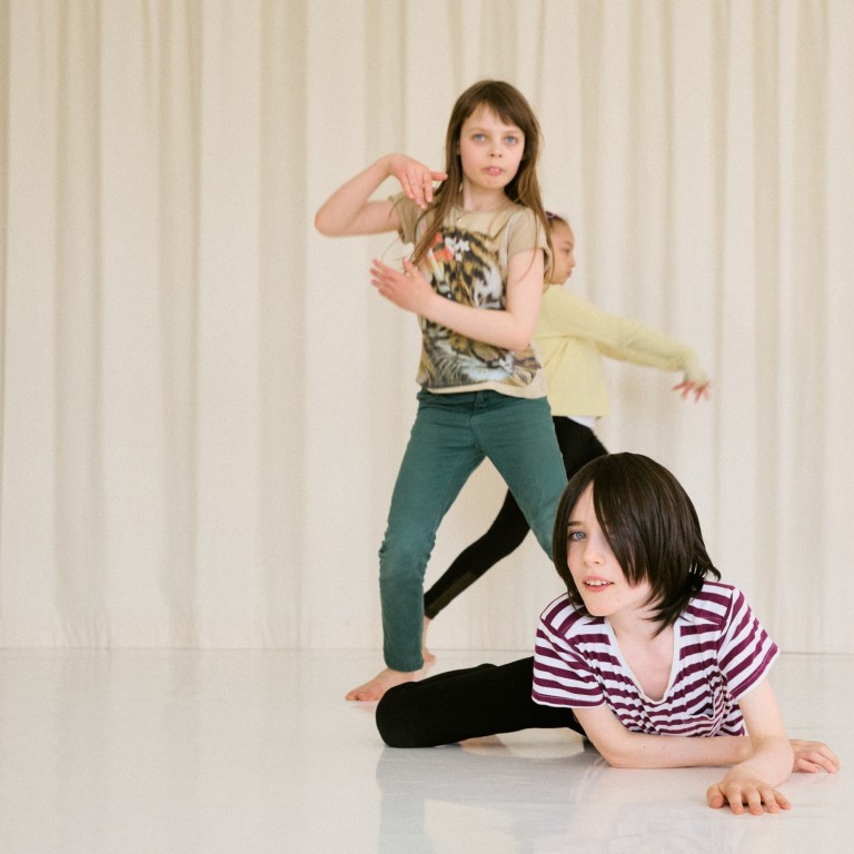 Three children dancing in a light space