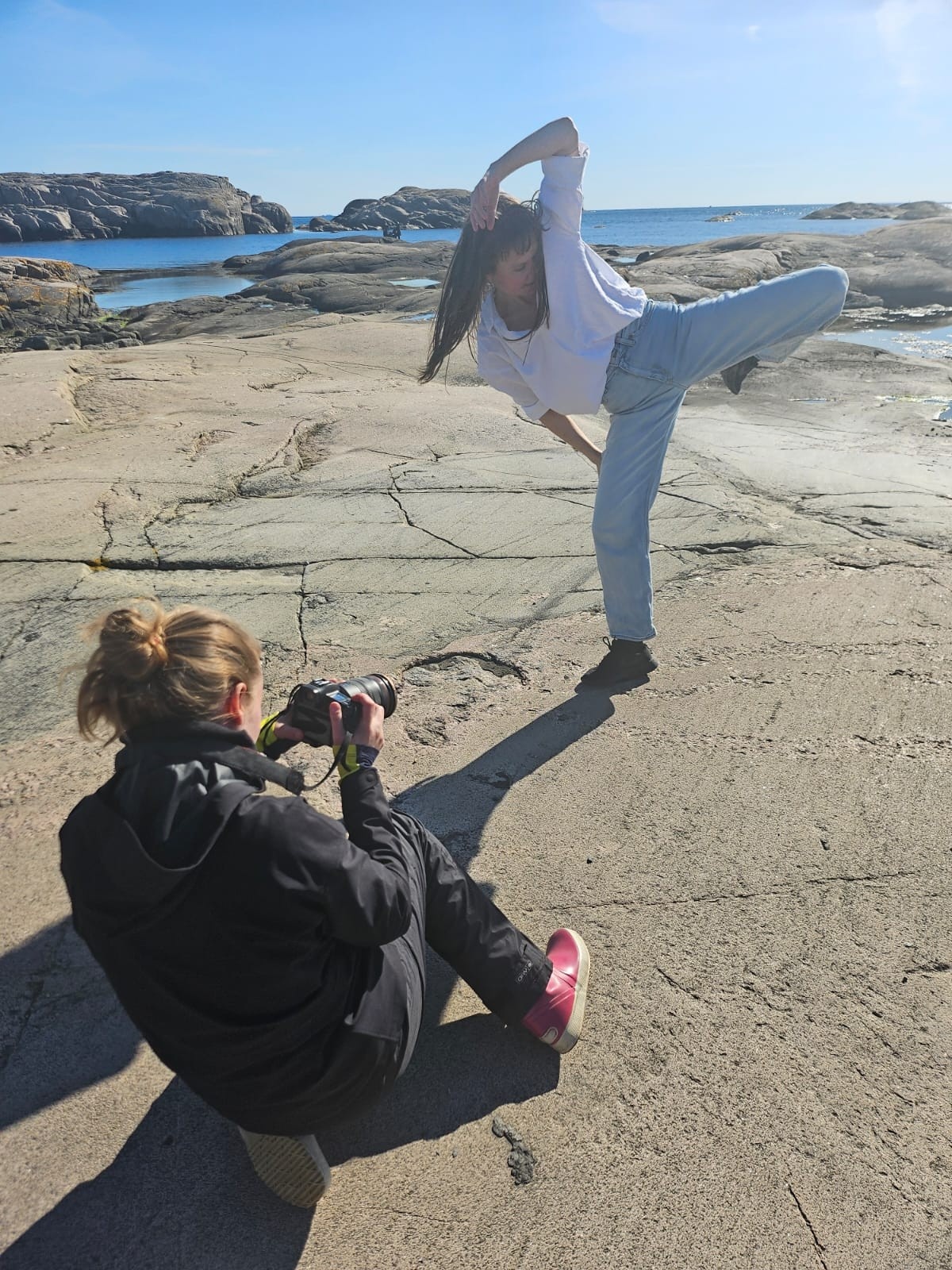 Nainen kuvaa toista kalliolla