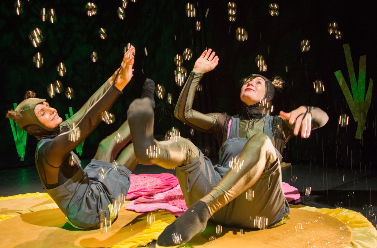 Kaksi hyönteiseksi pukeutunutta ihmistä leikkii saippuakuplilla