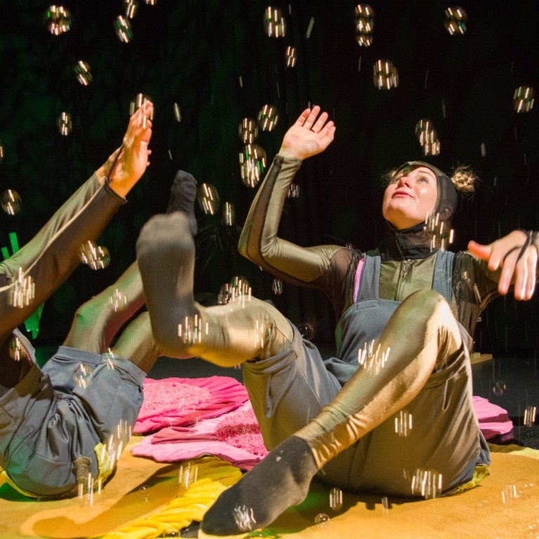 Kaksi hyönteiseksi pukeutunutta ihmistä leikkii saippuakuplilla